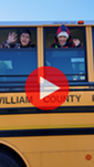 two students waving through open school bus windows