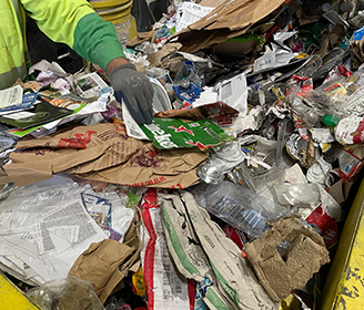 Gloved hand sorting recyclable material on a metal table