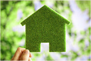 Grassy green house cutout held by hand