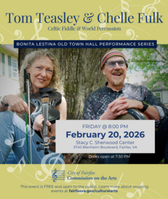 Woman holding a fiddle and a man crossing arms over a drum sit on the ground leaning on a tree trunk 