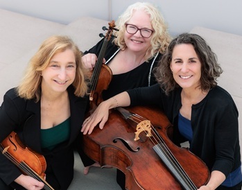 three women sitting looking up at the viewer and holding stringed instruments