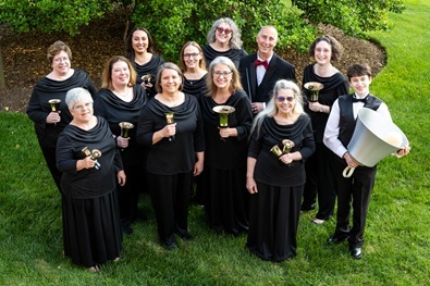 Group of about a dozen people dressed in formal black holding handbells and looking up at the viewer