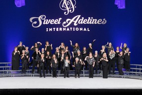Sweet Adelines with group of women in black dress standing on risers and facing the viewer