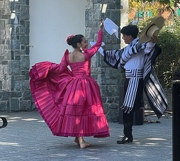 A couple dressed in Latin folkloric costume dancing outdoors on a stone stage