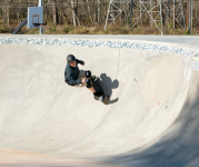 Image of person riding a skateboard wearing a helmet and knee pads