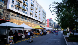 Image of people walking by white tents in Mosaic