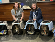 Two FCAS staff members with cats at the airport.