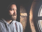 man with a beard looking out the window