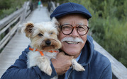 Photo of an older man hugging his pet dog and smiling. 