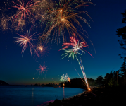 Image of fireworks over a lake as the sun sets in the background