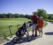 Image of a father and son on the golf course, wheeling a golf bag