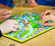 Image of a board game, with hands moving pieces across the board