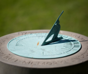 Image of a blue sundial outside with green grass in the background 