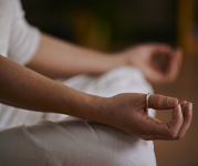 Image of a person sat with their legs crossed with their hands placed on their knees. Their palms are facing up