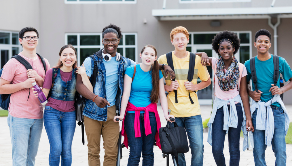 Image of high school students standing in a line outside of school.