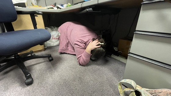 Employee under a desk during an earthquake drill