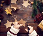 Image of a child's hands holding scissors and cutting out paper stars. 