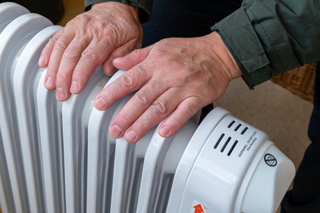 man warming his hands on a space heater
