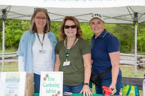 three women posing for a photo at a table at an outdoor event