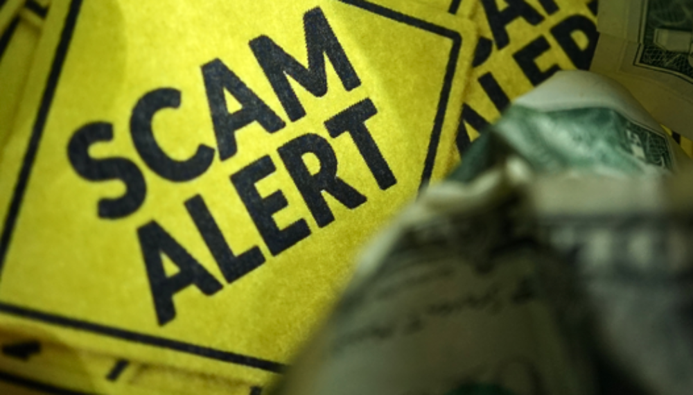 Image of a yellow sign with the text "Scam alert."