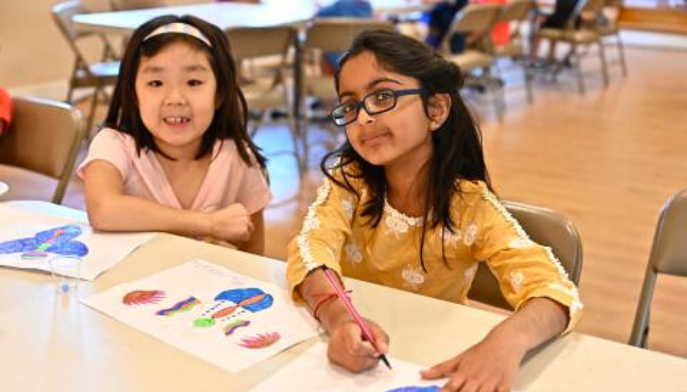 Image of two girls drawing and painting at a table.