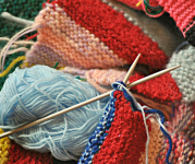 Image of a pile of yard and the start of a knitted project with knitting needles crossed over each other.