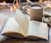 Image of an opened book next to a mug of coffee. 