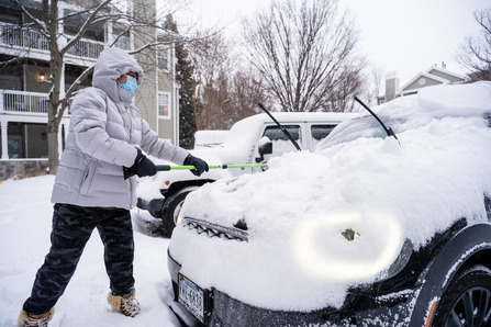 person clearing snow off car