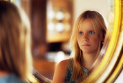 young woman looking in mirror
