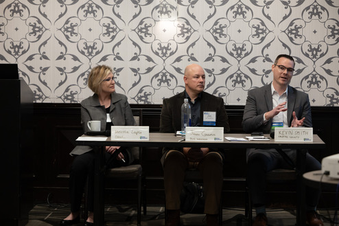 three people sitting at a table for a presentation