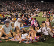 Image of a family sitting on a blanket on the grass.