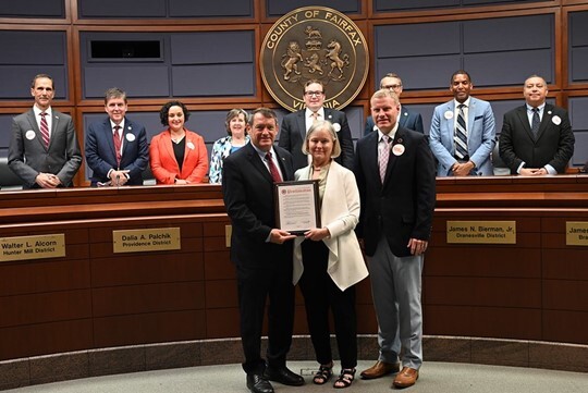 three people posing with a proclamation in front of the board of supervisors