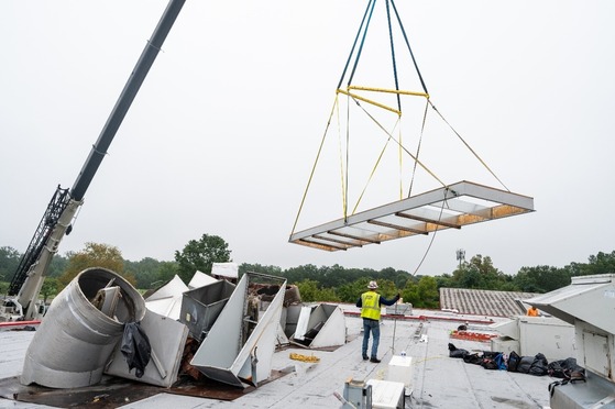 photo of a crane lowering a larger duct onto a roof