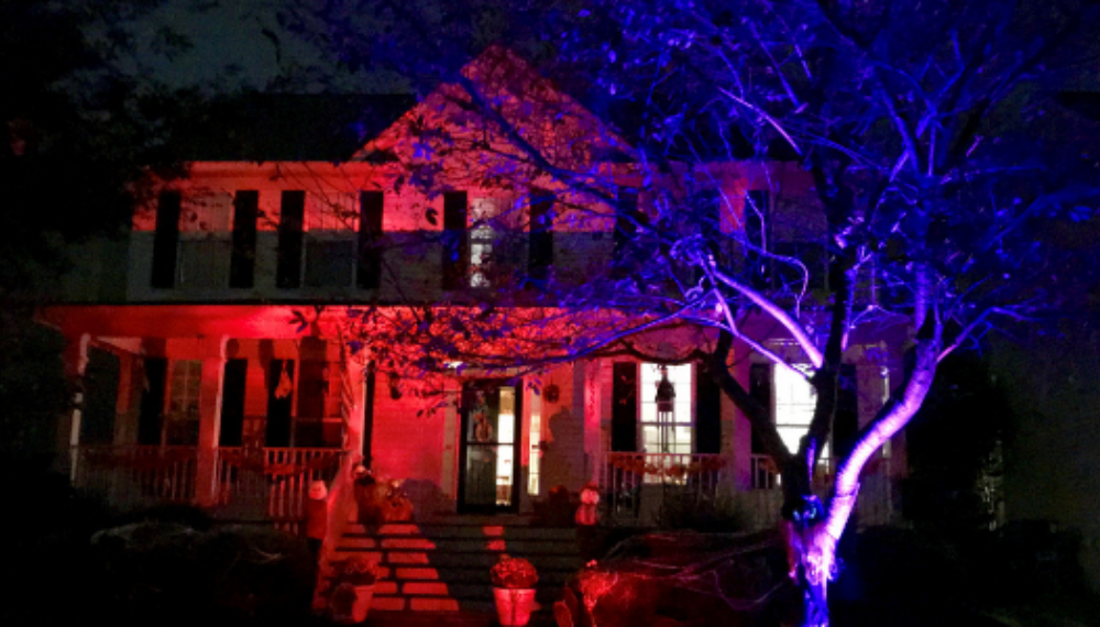 A house lit up in orange and purple for Halloween.