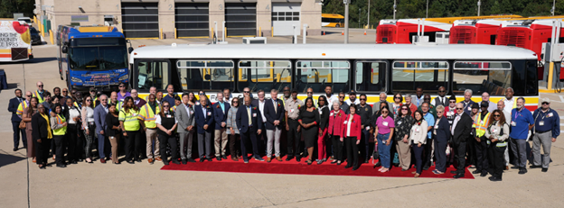 large group photo of staff standing in front of a connector bus