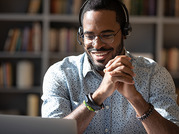 smiling man wearing headphones looking at laptop