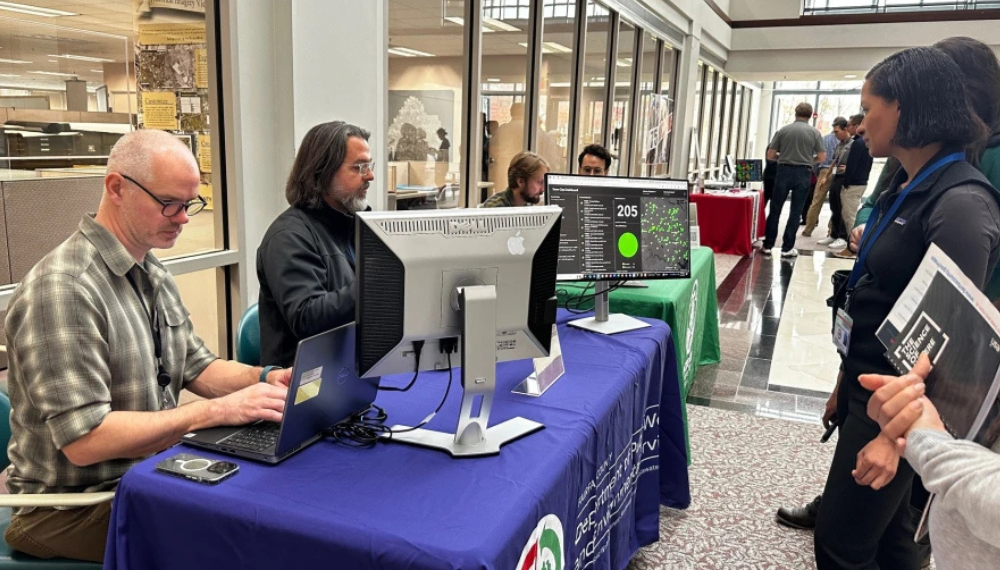 People gather at a table to view a GIS map at a previous GIS Day.