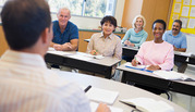 A man faces a classroom of seated smiling older adults.