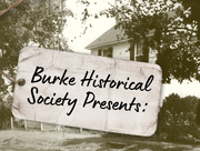 Background is an sepia photo of a wooden house with a piece of old paper in the foreground that reads Burke Historical Society presents