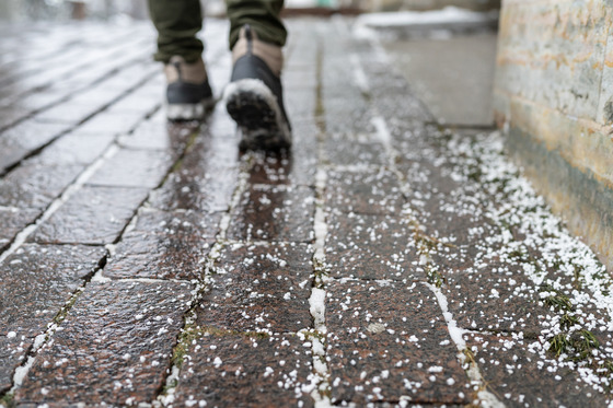 salt grains on icy sidewalk surface in wintertime