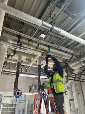 photo of man on ladder fixing a pipe