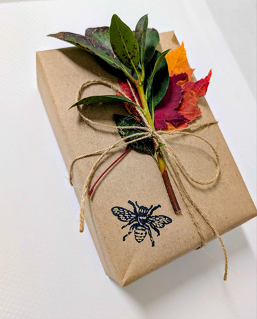 photo of a gift with sustainable wrapping, leaves and a stamp of a bee