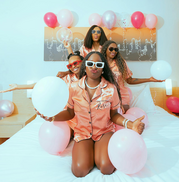 group of women in matching pajamas on bed with ballons