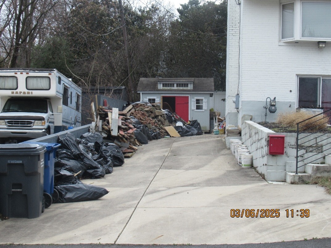 Residential driveway adjacent to another neighbor, with stored debris