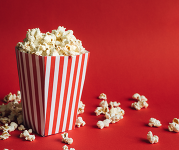 A red and white striped bucket filled and overflowing with popcorn.