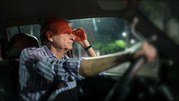 An older man squints at the road while driving at night.