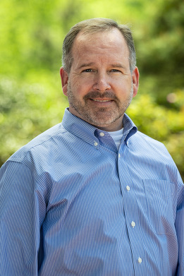 headshot of man in blue plaid shirt 