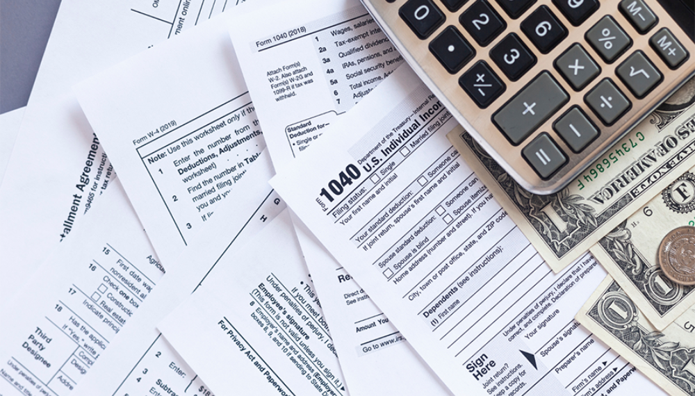 A 1040 document, a calculator and dollar bills to represent the tax season.