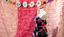 A dress on a mannequin in front of a sequined pink wall. 