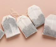 Dry tea bags against a pink background. 